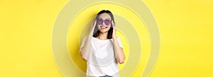 Fashion and lifestyle concept. Stylish asian woman trying new sunglasses in heart-shape, going on vacation, smiling