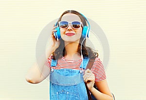 Fashion lifestyle portrait of happy woman is listens to music in headphones over white