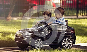 Little boy and girl driving toy car in a park