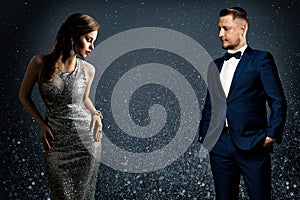 Fashion Luxury Couple. Glamour Woman and Handsome Man. Elegant Pair in evening Dress and Suit. Sparkling Background