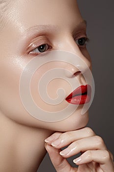 Fashion make-up & cosmetics. Glamour model face with bright red lips, clean shiny skin