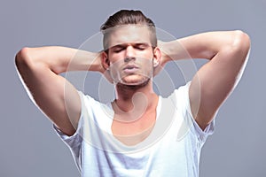 Fashion man with eyes closed and hands behind head