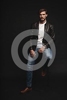 Fashion man, Handsome serious beauty male model portrait wear leather jacket, young guy over black background.