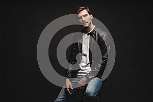 Fashion man, Handsome serious beauty male model portrait wear leather jacket, young guy over black background.