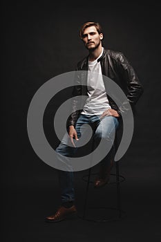 Fashion man, Handsome serious beauty male model portrait wear leather jacket, young guy over black background.