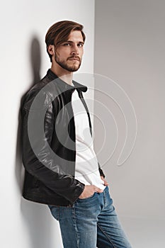 Fashion man, Handsome serious beauty male model portrait wear leather jacket, young guy over white background.