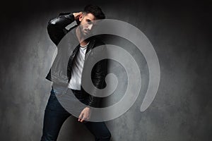 Fashion man in leather jacket posing with hand behind head