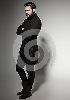 fashion man model in black sweater, jeans and boots posing dramatic