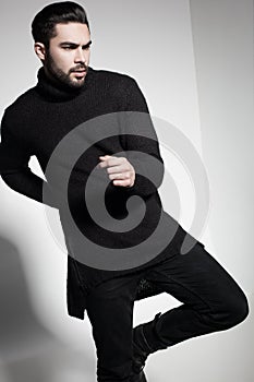 fashion man model in black sweater, jeans and boots posing dramatic