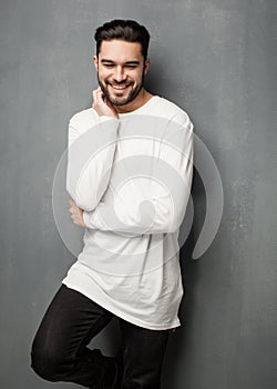 fashion man model in white sweater, jeans and boots smiling