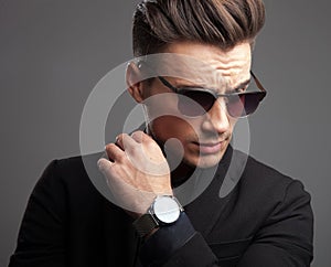 Fashion man showing his watch and looking down to side