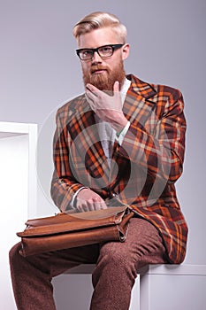 Fashion man sitting and playing with his beard