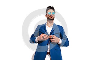 Fashion man wearing rings and sunglasses unbuttoning his coat