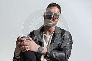 Fashion man with wet hair wearing sunglasses and holding knee up