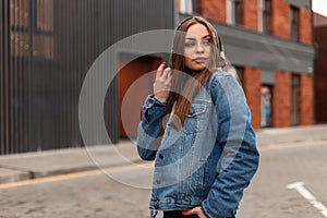 Fashion model american young pretty hipster woman in stylish denim jacket walks in the city. Fashionable urban girl in jeans