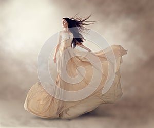 Fashion model in beautiful beige flowing chiffon dress