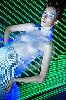 Fashion model beautiful girl in fashionable clothes in ultraviolet light, showing different poses. Beauty body and face.