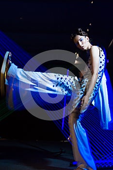 Fashion model beautiful girl in fashionable clothes in ultraviolet light, showing different poses. Beauty body and face.