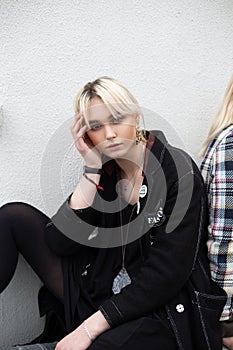 Fashion model beautiful young blonde woman in black fashionable clothes is resting on street near vintage building. Modern