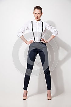 Fashion model in black trousers and top posing over white