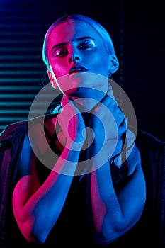 Fashion model blonde woman in colorful bright neon lights posing in studio.