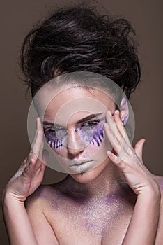 Fashion model with colorful make-up and blue glitter and sparkles on her face and body.