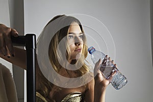 Fashion model drinking water from bottle in studio