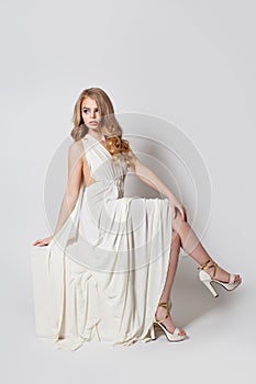 Fashion  model girl in white dress and legs in high heels shoes on white background