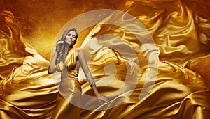 Fashion Model in Gold Dress, Beauty Woman Posing Flying Cloth photo