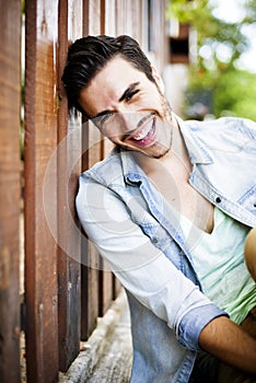 Fashion model leaning against a wooden fence