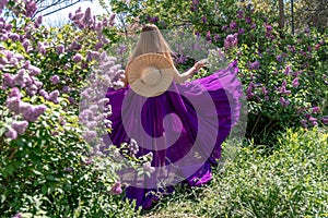 Fashion Model in Lilac Flowers, Young Woman in Beautiful Long Dress Waving on Wind, Outdoor Beauty Portrait in Blooming