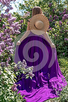 Fashion Model in Lilac Flowers, Young Woman in Beautiful Long Dress Waving on Wind, Outdoor Beauty Portrait in Blooming