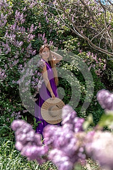 Fashion Model in Lilac Flowers, Young Woman in Beautiful Long Dress Waving on Wind, Outdoor Beauty Portrait in Blooming