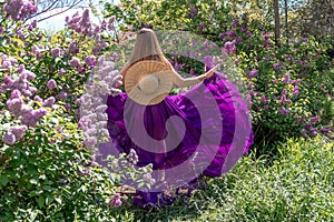 Fashion Model in Lilac Flowers, Young Woman in Beautiful Long Dress Waving on Wind, Outdoor Beauty Portrait in Blooming