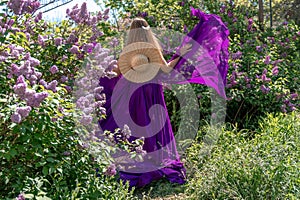 Fashion Model in Lilac Flowers, Young Woman in Beautiful Long Dress Waving on Wind, Outdoor Beauty Portrait in Blooming