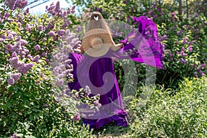 Fashion Model in Lilac Flowers, Young Woman in Beautiful Long Dress Waving on Wind, Outdoor Beauty Portrait in Blooming