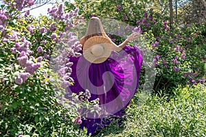 Fashion Model in Lilac Flowers, Young Woman in Beautiful Long Dress Waving on Wind, Outdoor Beauty Portrait in Blooming