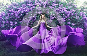 Móda v šeřík květiny mladá žena v krásný dlouho šaty mávání na vítr venkovní krása portrét v kvetoucí zahrada 