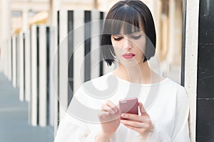 Fashion model with mobile device. Woman with red lips use on smartphone in paris, france. Woman with brunette hair hold mobile pho