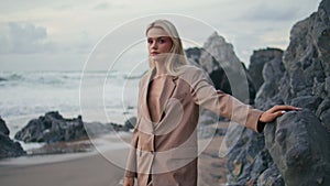 Fashion model posing ocean coast in elegant suit. Attractive blonde at sea waves