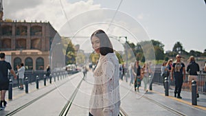 Fashion model posing street turning to camera at sun beams town. Carefree woman