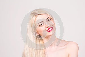 Fashion model posing at studio. Smiling beautiful woman with long straight blond hair, white teeth, red lips and make-up