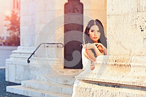 Fashion model or princess in dress. Bride girl at wedding ceremony in castle. Woman at stone ancient column in summer