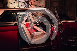 Fashion model in red dress in a retro car invites you to come in