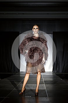 Fashion model  on runway in fur coat and evening dress