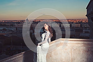 Fashion model style and hairstyle. Woman in white wedding dress on evening city view, fashion. Sensual woman with long