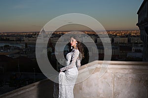 Fashion model style and hairstyle. Woman in white wedding dress on evening city view, fashion. Sensual woman with long