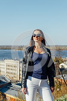 Fashion model in sunglasses and black leather jacket posing outdoor