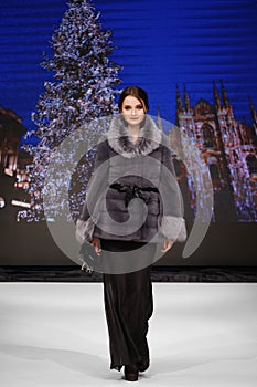 Fashion model walks  on runway in fur coat