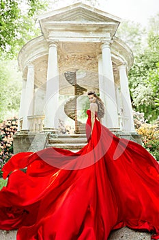 Fashion Model Waving Long Fluttering Red Dress, Woman in Garden, Old White Alcove in Flowers